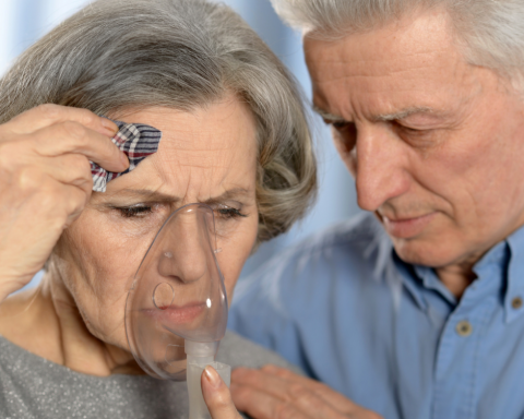 Pessoa idosa com alergia respiratória sendo acudida por parceiro idoso.